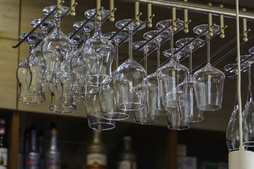 wine Glass suspended above a bar. blurry background.