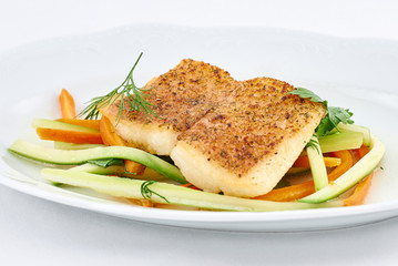 Delicious fried fish on fresh pepper strips on a white plate.