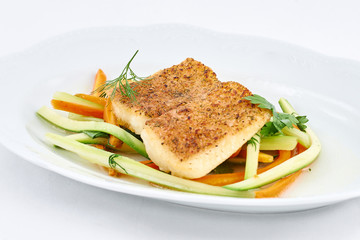Delicious fried fish on fresh orange and green pepper strips on a white plate.