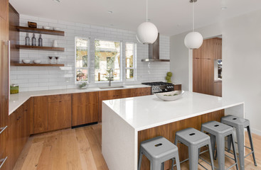 Modern Kitchen Interior in New Luxury Home with White Subway Tile, Oven and Range, Island, and Hardwood Cabinets and Floors