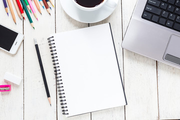 Empty notebook and colorful pencils on white wooden table