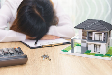 Stressed woman with running out of money in piggy bank and her house - dept and installment payment concept