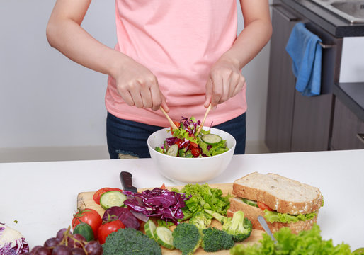 close up woman mixing salad while cooking in kitchen