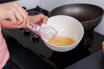 close up of hand cooking and whisking eggs in a bowl in kitchen