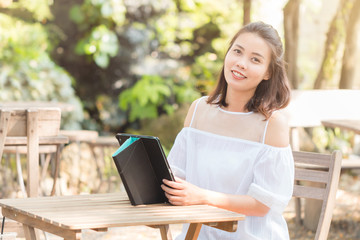 Obraz premium Portrait of Attractive young Asian woman wearing white casual using tablet smiling and looking at camera. Technology, Internet, and Business concept.