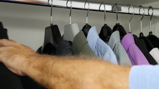 Man Looking in a Wardrobe with Suits and Shirts