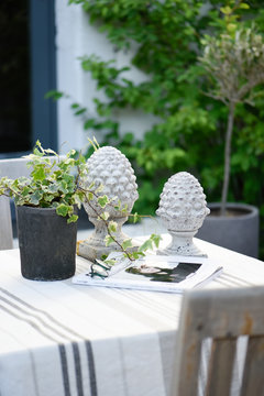Table covered with white, gray and beige linen, ivy and magazine for a moment of relaxation on the terrace