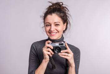 Portrait of a young woman with a camera in studio.