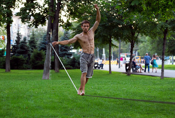 Slackline in the summer park Against the background of city bustle