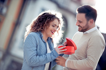 Smiling boy giving to his girlfriend a gift