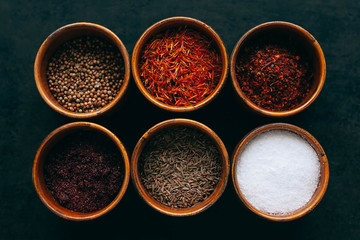 Set of spices on dark grey background.  Food art concept. Composition of bottles with colored herbs and spices.