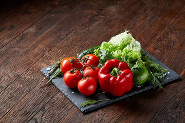 Close-up still life of assorted fresh vegetables and herbs on vintage wooden background, top view, selective focus.