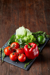 Close-up still life of assorted fresh vegetables and herbs on vintage wooden background, top view, selective focus.