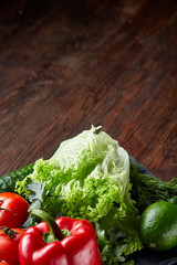 Close-up still life of assorted fresh vegetables and herbs on vintage wooden background, top view, selective focus.