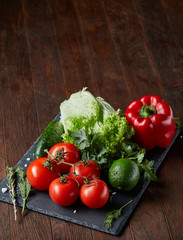 Close-up still life of assorted fresh vegetables and herbs on vintage wooden background, top view, selective focus.