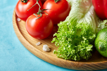 Refreshing close-up still life of assorted fresh vegetables and herbs on blue background, top view, selective focus.