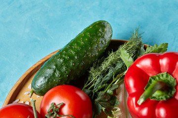 Refreshing close-up still life of assorted fresh vegetables and herbs on blue background, top view, selective focus.