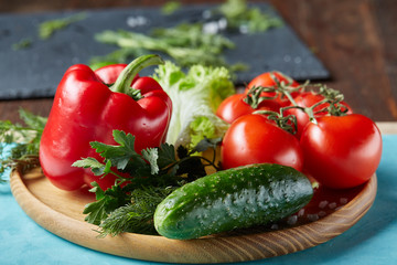 Refreshing close-up still life of assorted fresh vegetables and herbs on blue background, top view, selective focus.