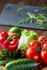 Close-up still life of assorted fresh vegetables and herbs on vintage wooden background, top view, selective focus.