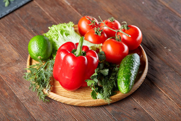 Close-up still life of assorted fresh vegetables and herbs on vintage wooden background, top view, selective focus.