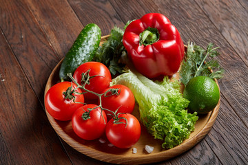 Close-up still life of assorted fresh vegetables and herbs on vintage wooden background, top view, selective focus.
