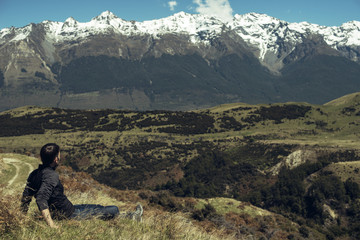 Fototapeta premium Hombre joven disfrutando de las vistas de un paisaje con montañas evadas en Nueva Zelanda