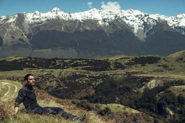 Fototapeta na wymiar Hombre joven disfrutando de las vistas de un paisaje con montañas evadas en Nueva Zelanda