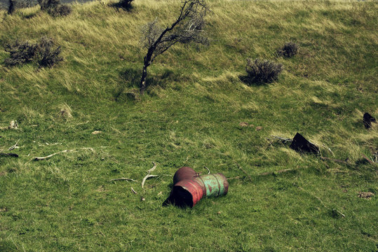 Imagen minimalista de dos bidones oxidados tirados y olvidados en medio del campo