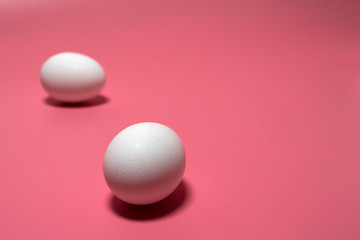 White eggs on pink background. Minimal Easter concept. Close up. Copy space. Birth theme.