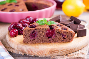 A piece of chocolate pie with a cherry on a table