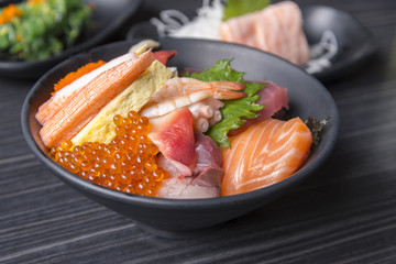 Premium fresh raw seafood mixed rice bowl (Kaisen-don/ Japanese tasty food), Japanese Rice with sashimi of tuna, Maguro, Otoro, salmon, squid and ikura (Salmon eggs) on wood background