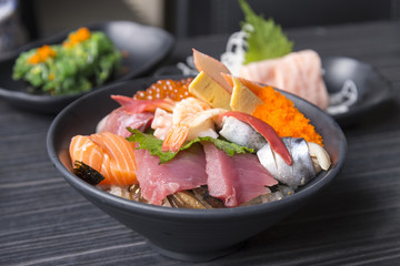Premium fresh raw seafood mixed rice bowl (Kaisen-don/ Japanese tasty food), Japanese Rice with sashimi of tuna, Maguro, Otoro, salmon, squid and ikura (Salmon eggs) on wood background