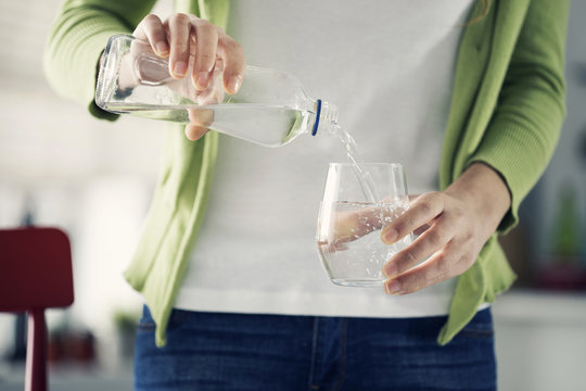 Woman  pouring water from bottle to glass