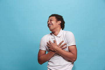 The happy business man standing and smiling against blue background.