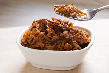 Pulled pork in a white dish with a fork