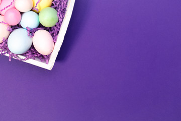 Multicolor eggs in a white tray. Creative Easter concept. Modern solid ultra violet  background.