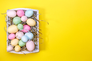 Fototapeta na wymiar Multicolor eggs in a white tray. Creative Easter concept. Modern solid yellow background.