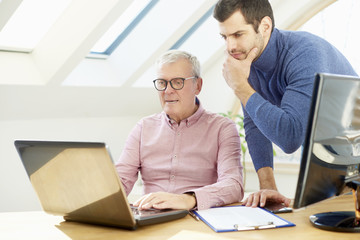 Brainstorming at the office. Young financial assistant businessman working with elderly financial businessman and consulting about business. Teamwork. 