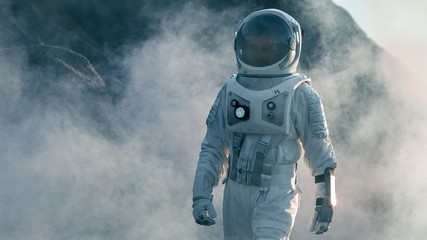 Shot of Astronaut Walking on Alien Rocky Planet that is Covered with Gas and Smoke. Humans Overcoming Difficulties. Scientific Progress.