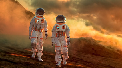 Two Astronauts Wearing Space Suits Walk Exploring Mars/ Red Planet. Space Travel, Exploration and...