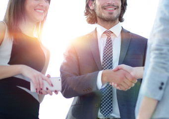 Businesspeople  shaking hands against room with large window loo