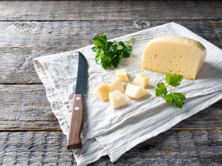 Piece of cheese with parsley on a linen towel Rustic wooden background
