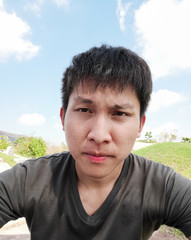 Asian man has selfie with hot feeling and boring at Qingming Festival or Tomb Sweeping day in Saraburi, Thailand.