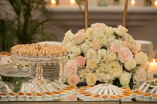 Vintage reception´s catering table with desserts and flowers. Social event concept. Wedding sweets: Macaroons, cupcakes and flowers.