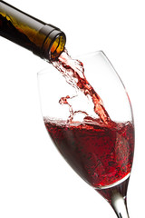 red wine poured from a bottle into a glass isolated on white