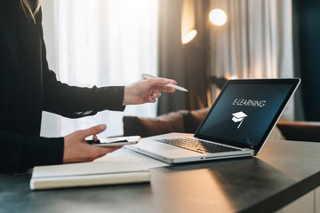 Woman standing near table,pointing pencil on laptop with inscription on screen e-learning, image of...