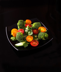 The vegetable salad with broccoli, tomatoes, cucumber, green onions and greens