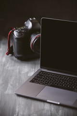Laptop and a camera on a dark wooden background.