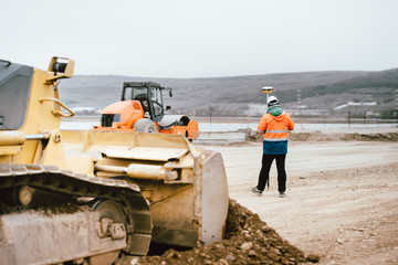 Surveyor engineer with GPS system outdoors at highway construction site, excavator and bulldozer details © aboutmomentsimages