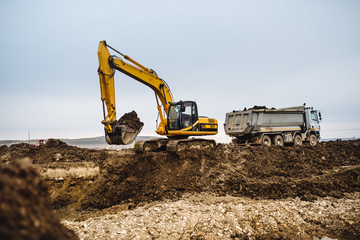 Industrial heavy duty machinery, details of excavator building highway and loading dumper trucks on construction site